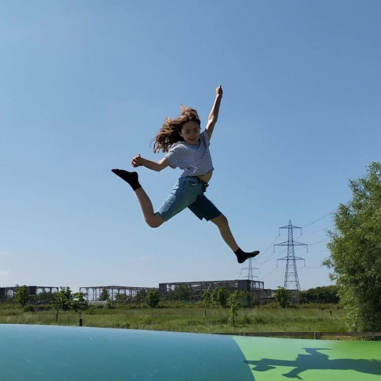 Summer Pass - unlimited visits - photo of a young girl jumping on a bouncy pillow, with blue sky background
