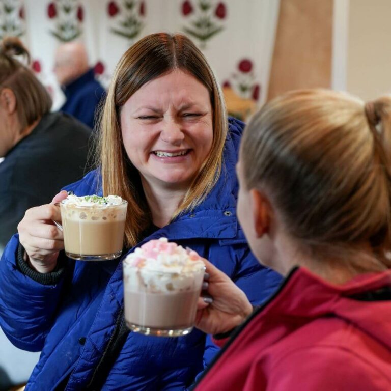 Mums Go Free offer - Photo of two women sitting in a cafe enjoying frothy hot chocolate drinks